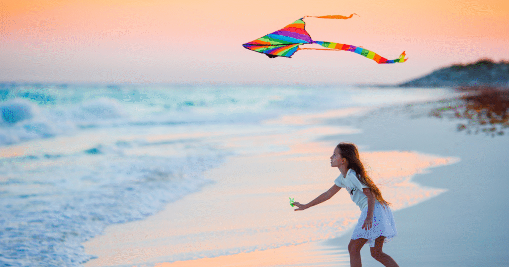 child flying kite on beach