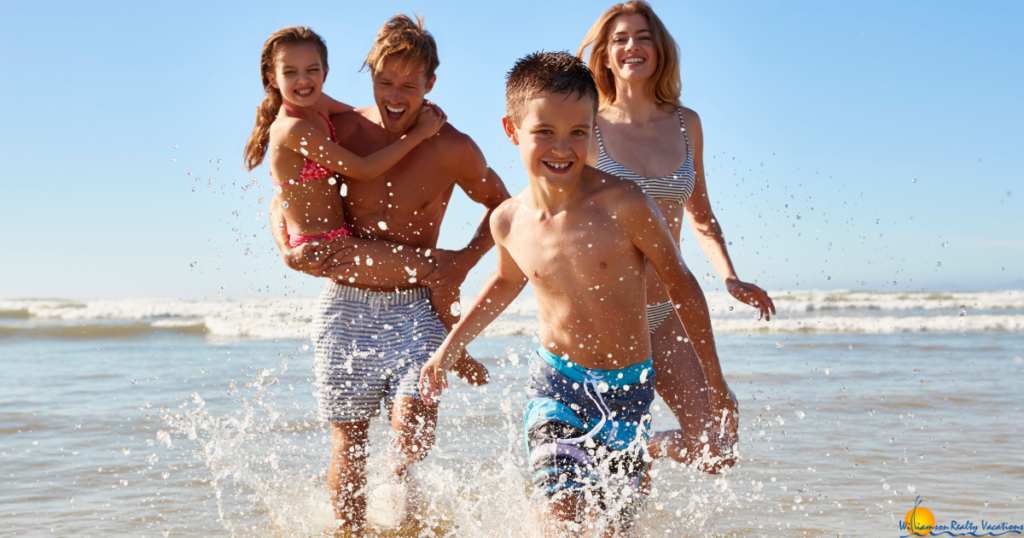 family of four running through water at the beach