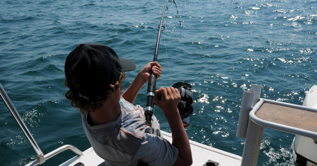 person fishing from back of boat