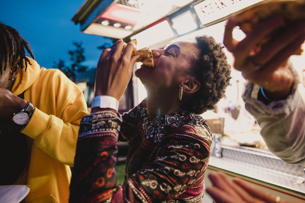 woman eating food outside a food truck at a festival