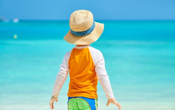 young boy wearing rash guard on the beach | Williamson Realty