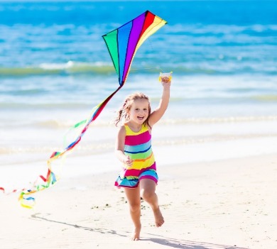 little girl flying a kite on the beach | Williamson Realty