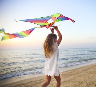 young girl on the beach with a kite | Williamson Realty