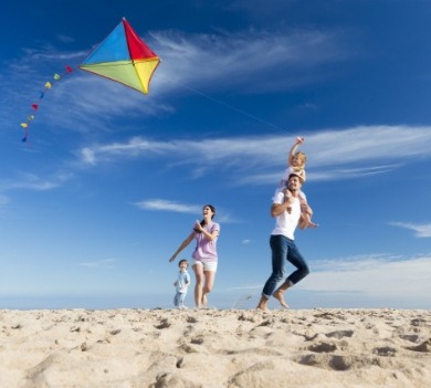 family flying diamond kite on the beach | Williamson Realty