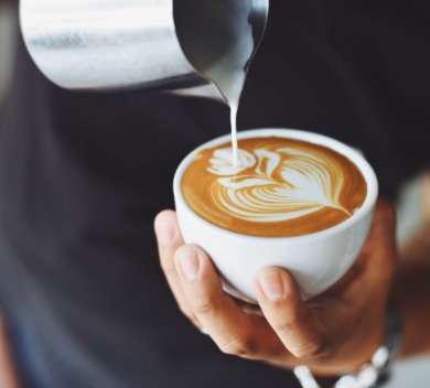 Barista pouring milk into coffee at coffee shop | Williamson Realty Vacations Ocean Isle Beach Rentals