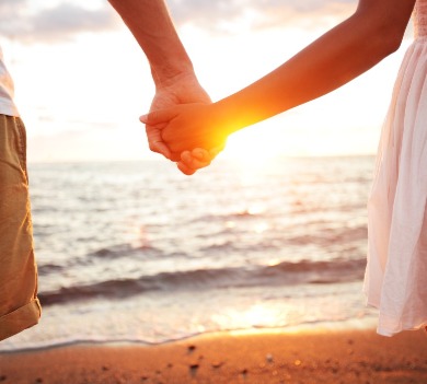 Couple holding hands on the beach at sunrise | Williamson Vacations Ocean Isle Beach Rentals