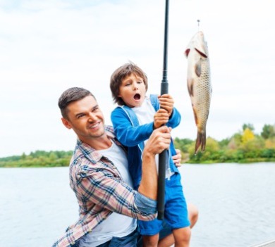 Man and young boy catching a fish from a dock  | Williamson Realty Vacations Ocean Isle Beach Vacation Rentals