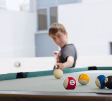 Boy shooting pool on a pool table | Williamson Realty Vacations Kid Friendly Ocean Isle Beach Rentals