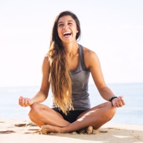Woman sitting on the beach doing a yoga pose | Williamson Realty Ocean Isle Beach NC Rentals